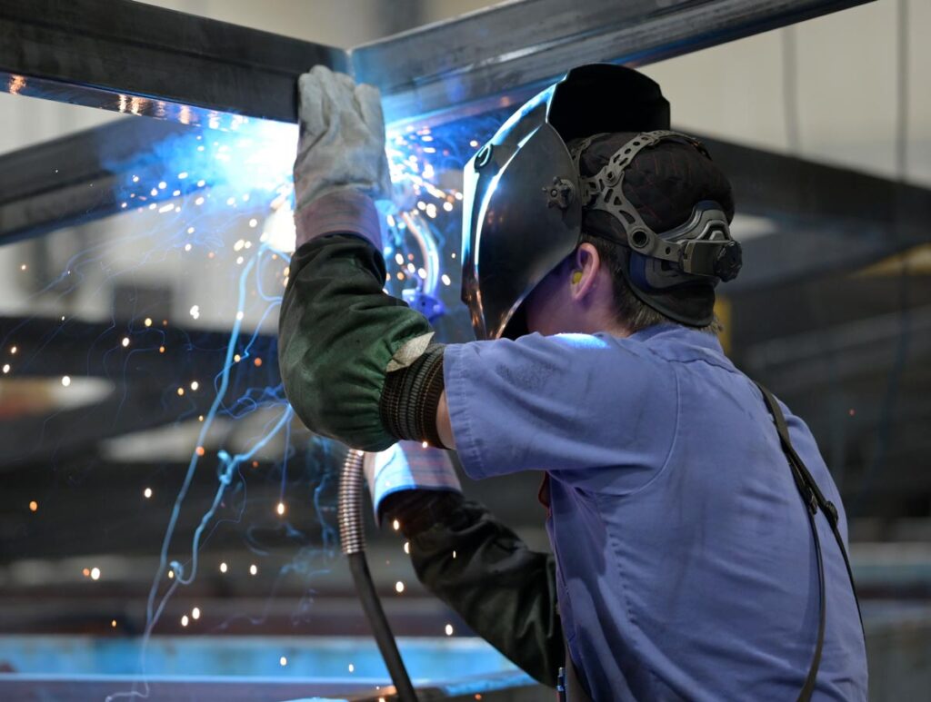 Welder working on a frame with blue sparks flying